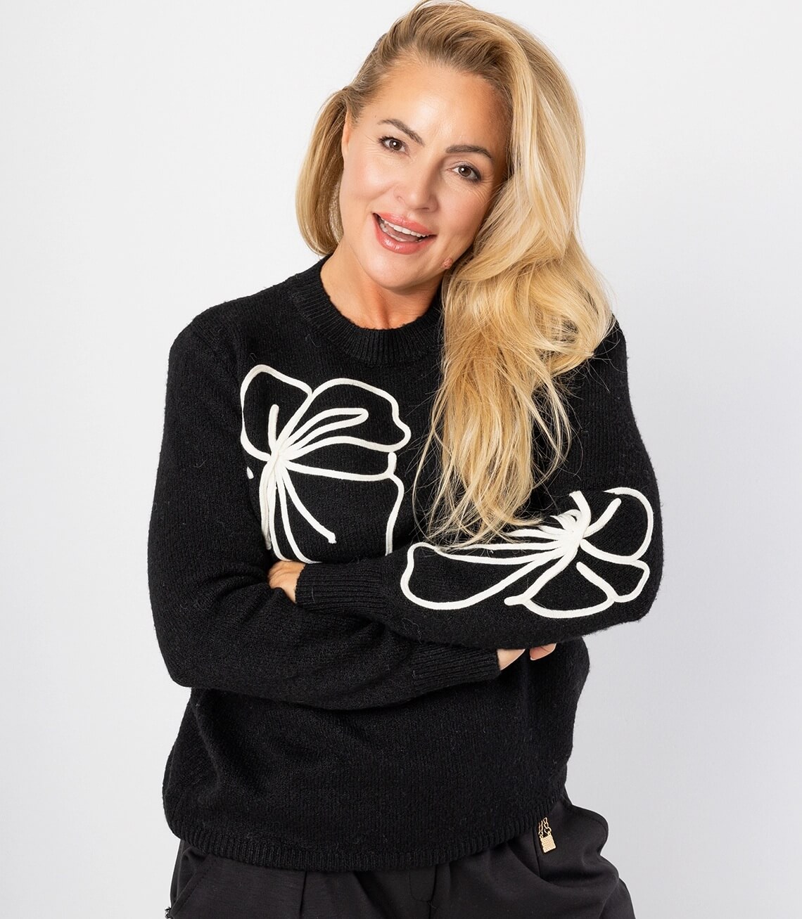 Damenpullover in Schwarz mit kontrastierenden weißen Blumenmustern an den Ärmeln, modisch und lässig.