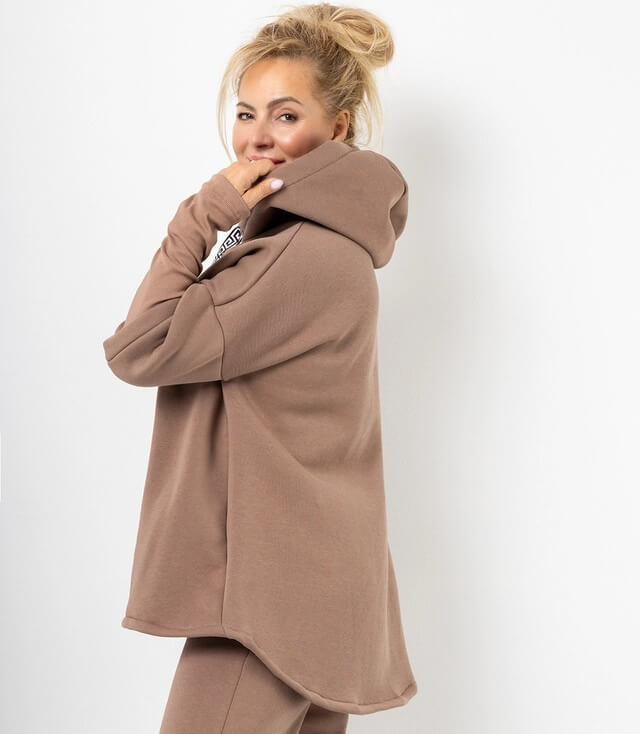 Model in braunem Oversize-Hoodie mit Kapuze und seitlichem Logo, lässige Mode für entspannte Tage.