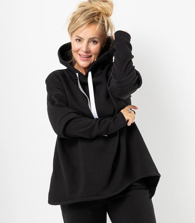 Schwarzer Sweater mit Kapuze und Kordelzug, lässig getragen von einer Frau mit fröhlichem Lächeln.