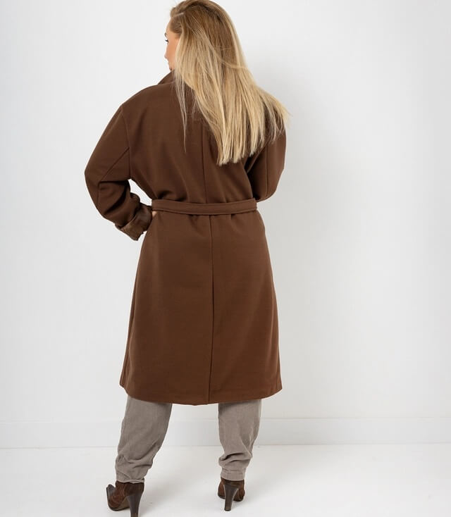 Rückansicht eines braunen Mantels mit Gürtel, kombiniert mit beigen Hosen und hohen Schuhen.