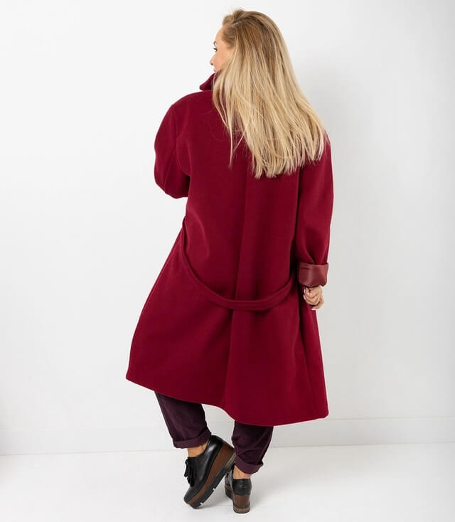 Hinteransicht des roten Mantels mit Gürtel, kombiniert mit schmalen Hosen und schwarzen Schuhen.