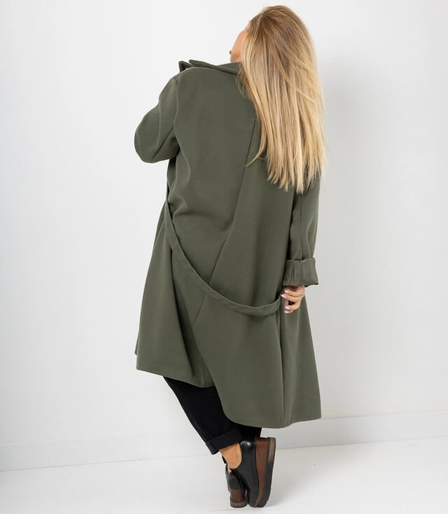 Dame trägt Mantel in Khaki von hinten, lässig mit langen Haaren und lässigem Outfit.