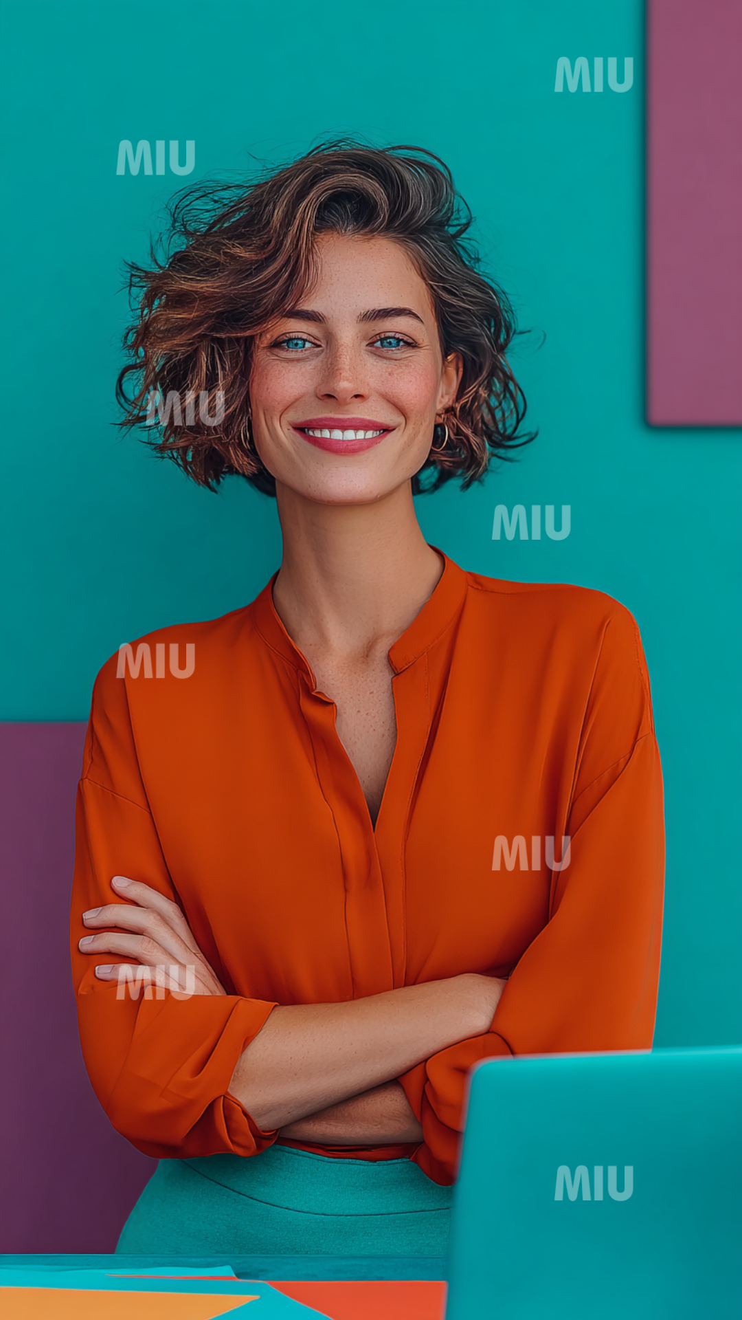 Entrepreneuse souriante aux bras croisés, dégageant une confiance naturelle et authentique, devant un fond coloré moderne.