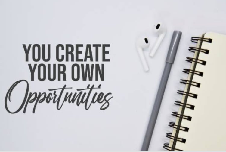 A flat lay image showing a spiral notebook, pen, and wireless earphones on a clean desk, with the text 'You Create Your Own Opportunities' in bold lettering. The image conveys a sense of empowerment and productivity, ideal for inspiring personal growth and success.