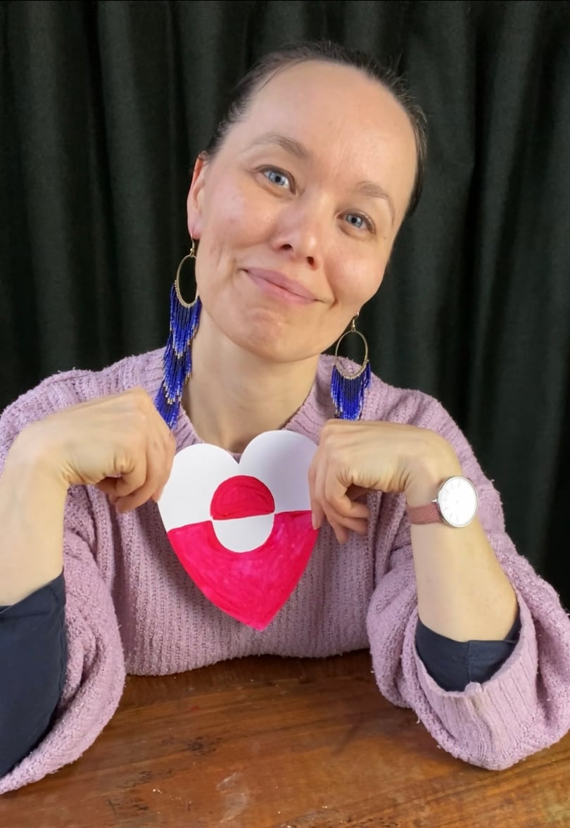 An Inuk woman holding a heart-shaped greenlandic flag to show appreciation