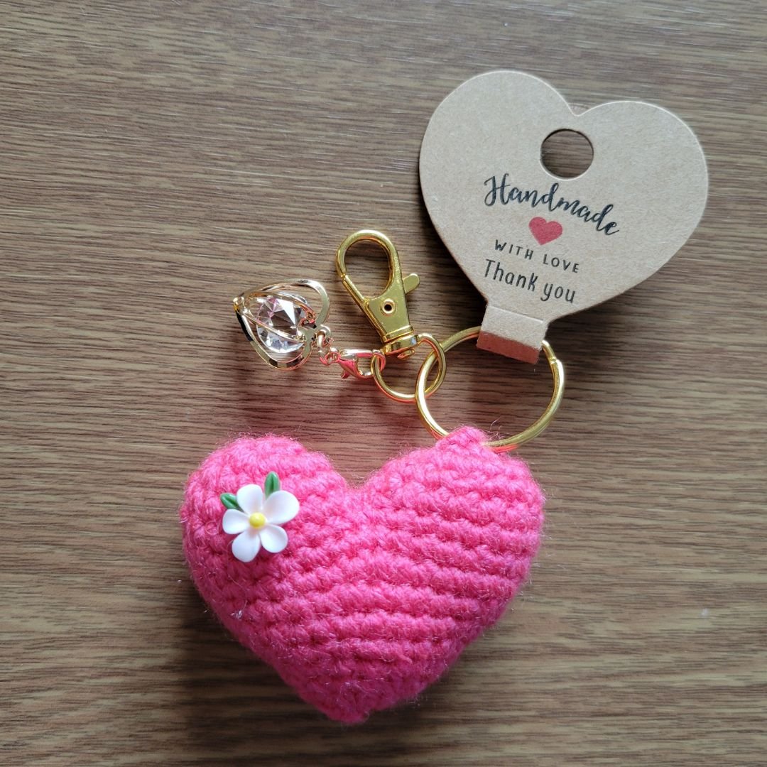Crochet pink heart keyring with crystal charm and gold clasp on wooden background