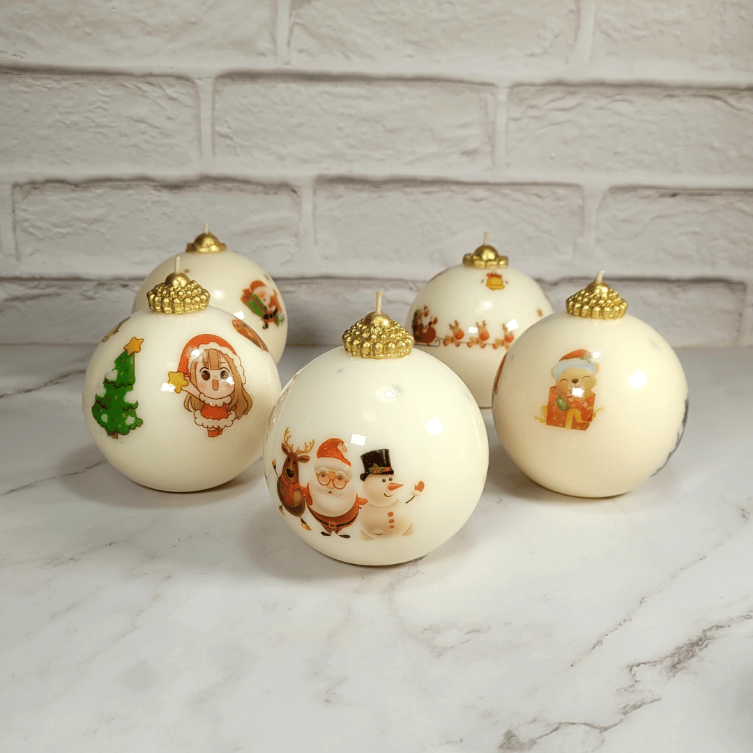 Glossy sphere candles with festive image decoration and handmade golden toppers