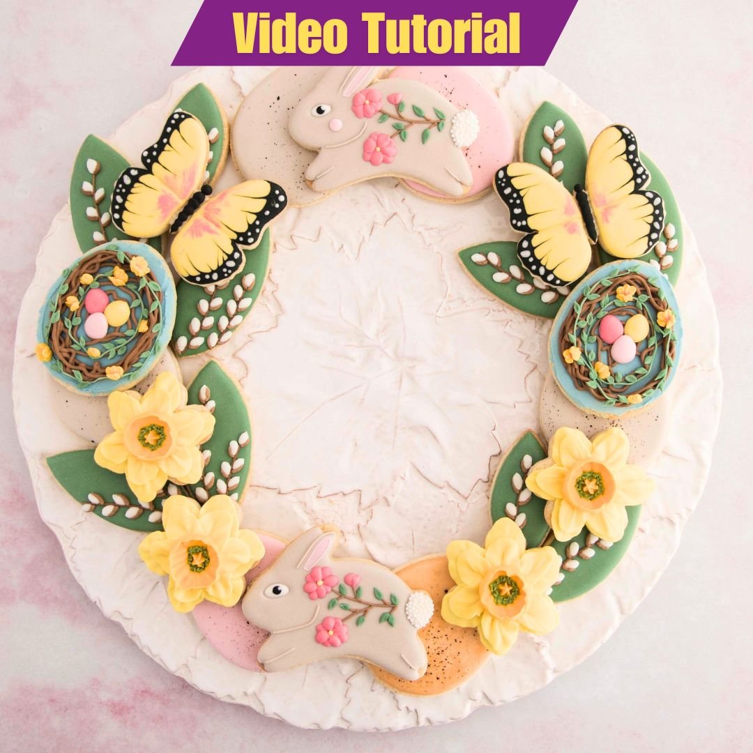 Decorated cookies arranged in wreath formation on a large plate.