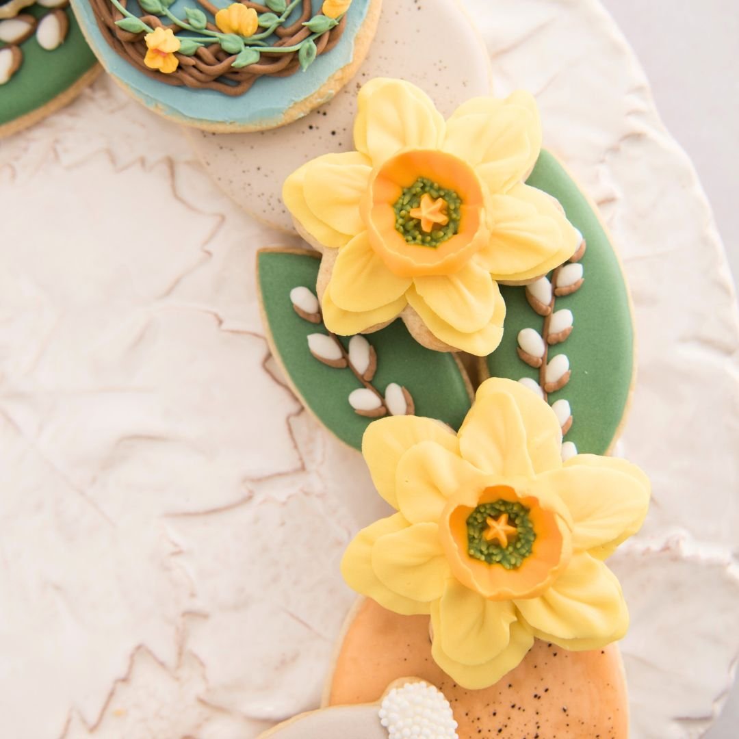 Yellow flower cookies decorated like daffodil on a platter.