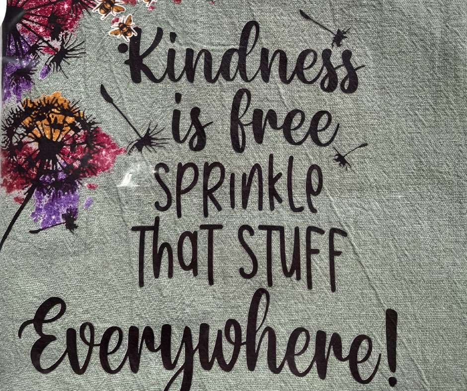 Customised Apron in eucalyptus green with dandelion motive and the words Kindness is free sprinkle that stuff everywhere.