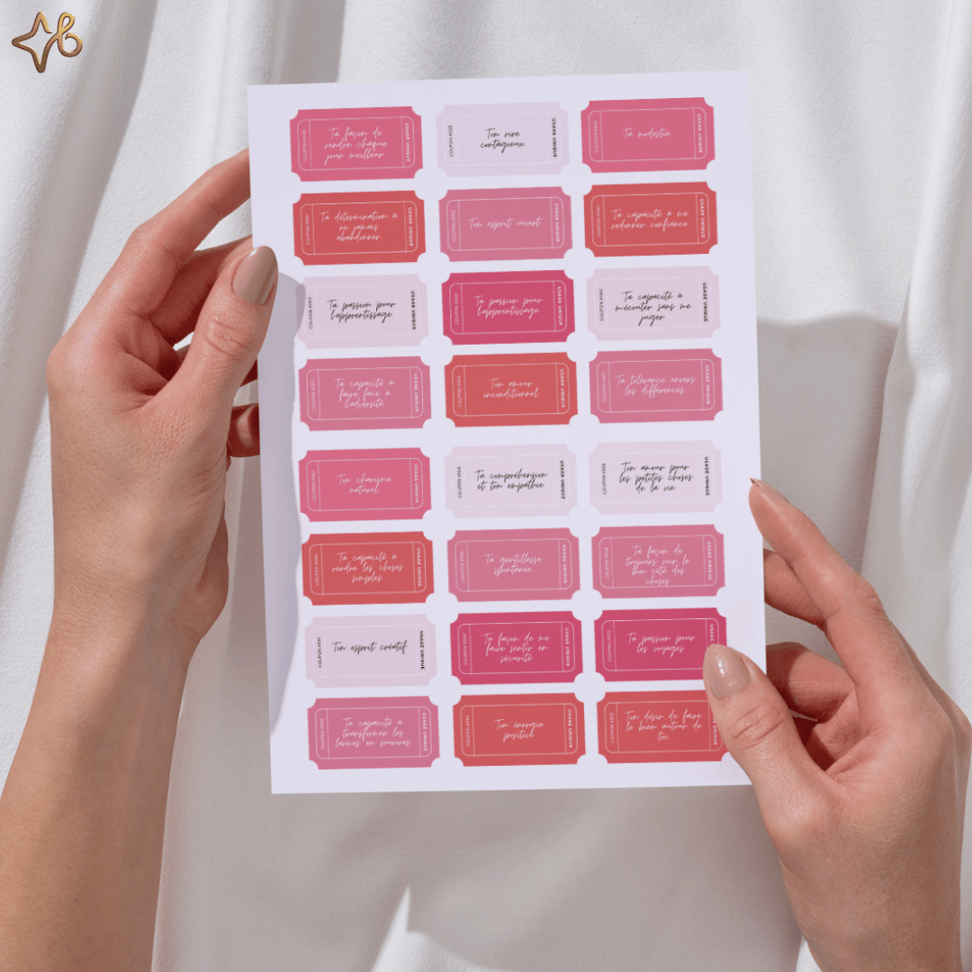 Mains tenant une planche de 365 mots doux imprimée, montrant la taille réelle des coupons et les différentes nuances de rose et rouge.