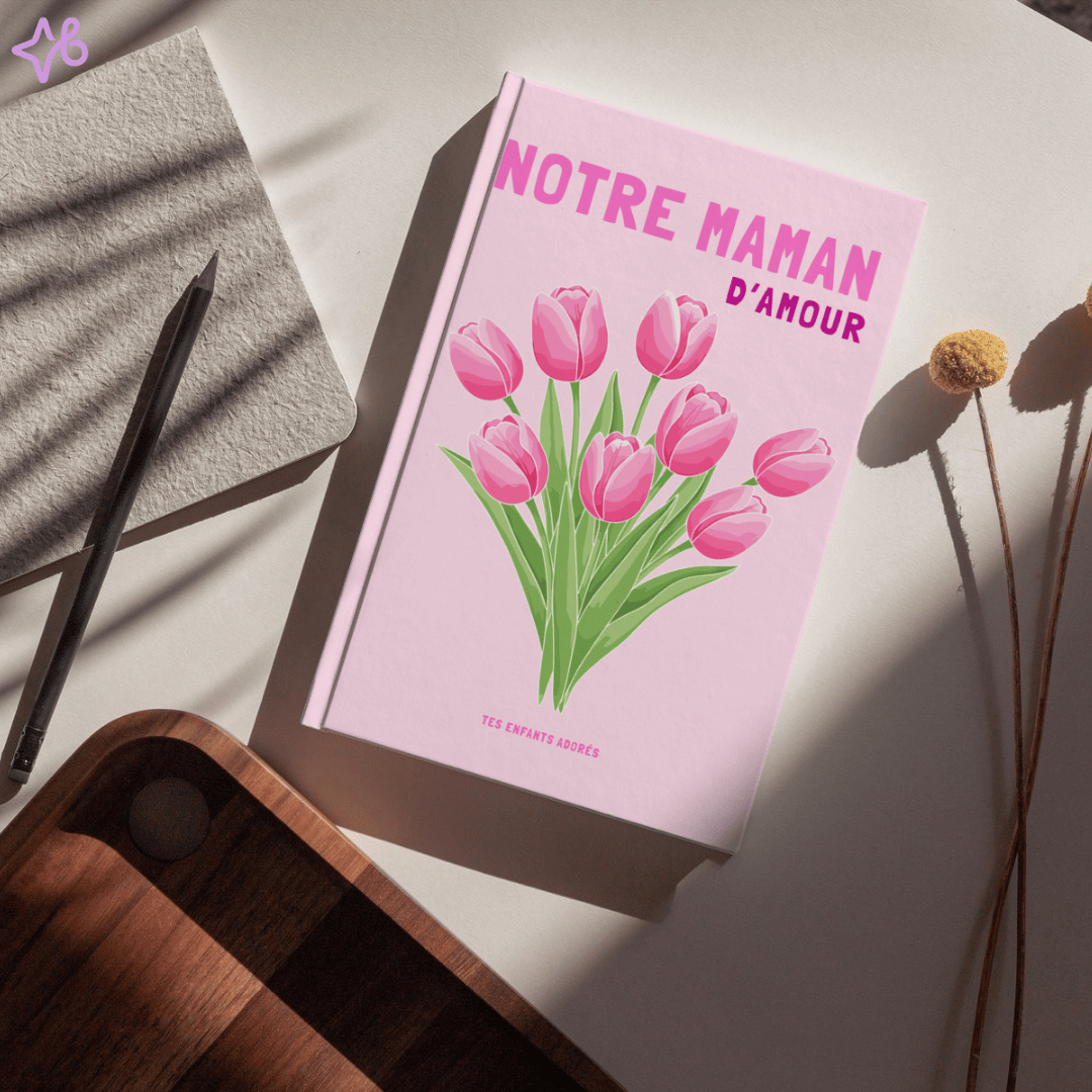 Livre photo souvenir "Notre maman d'amour" posé sur un bureau avec un crayon et des fleurs séchées.