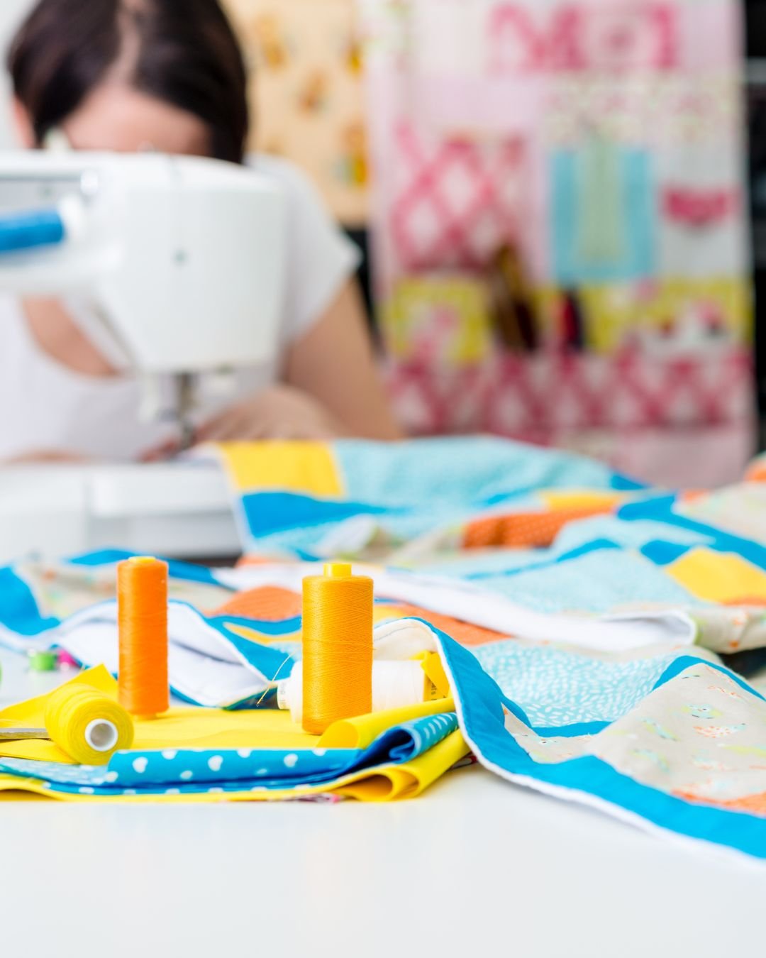 colourful image of someone at a sewing machine, bright fabrics in the front