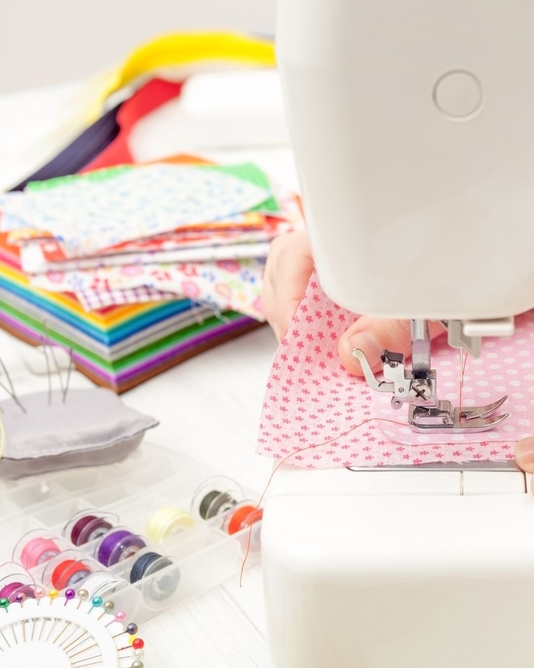 colourful fabrics and a hand using a sewing machine close up