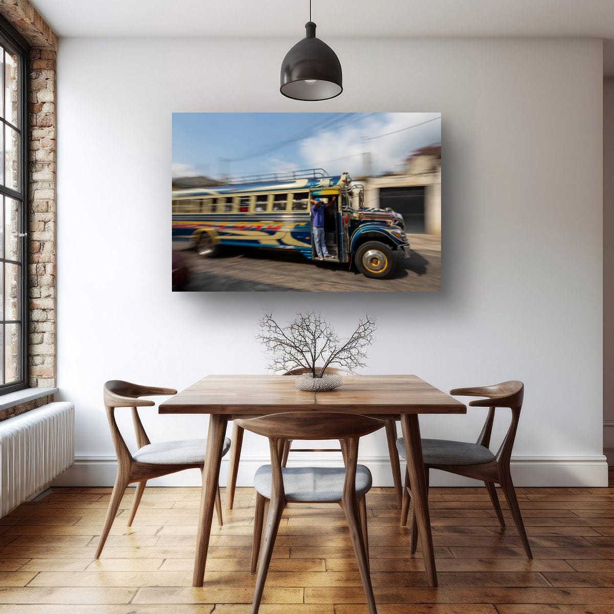 A large horizontal print displaying a colorful blue bus in motion hangs centered on a white dining room wall above a mid-century wooden table and chair set.