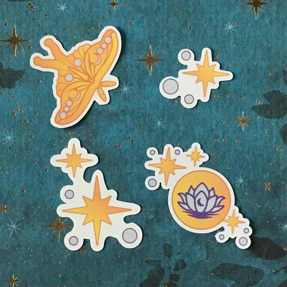 Four moon, moth and lotus and stars mini decals with sparkly lamination on display.
