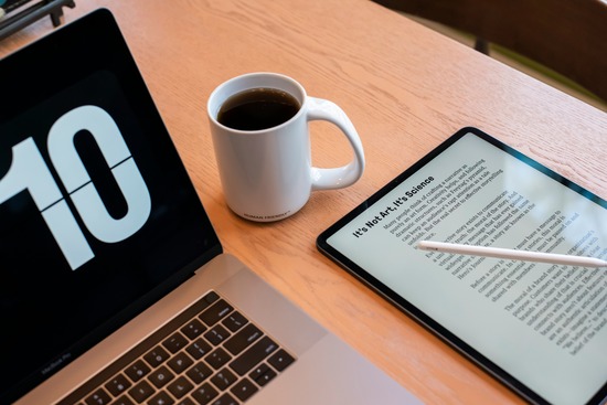 eBook reader beside a laptop with a cup of coffee