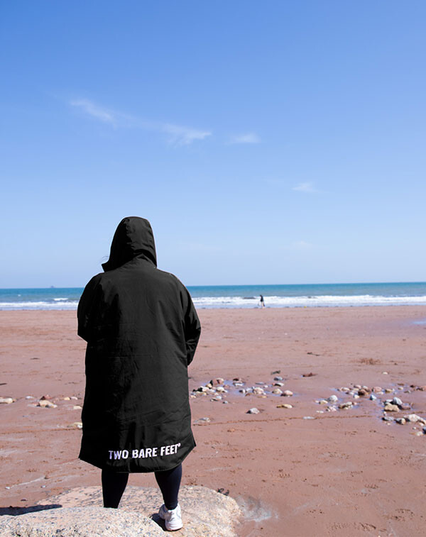 Person standing on a beach in the weatherproof changing robe