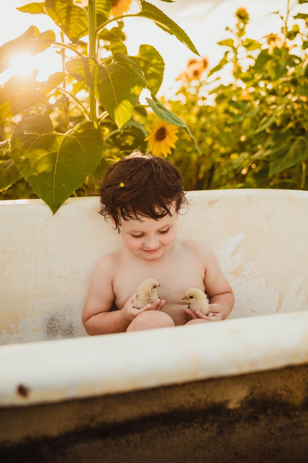 Child holding chicks in a bathtub