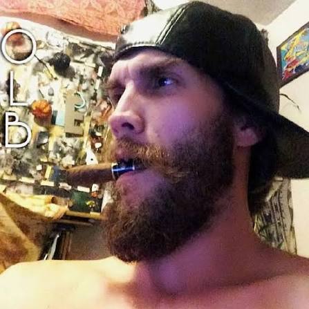 Bearded Oregon Leather boy smoking a cigar with a black leather hat backwards