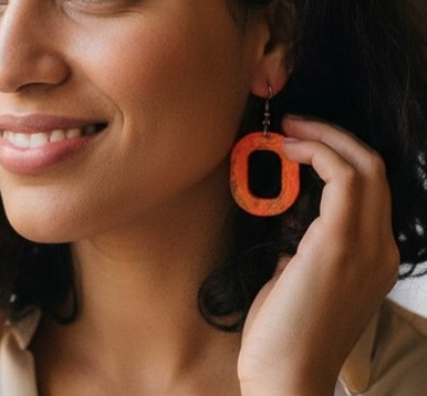 Close-up of orange marbled resin drop earring being worn