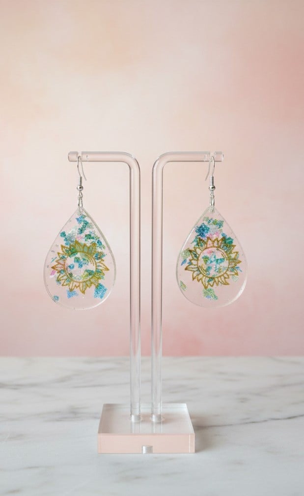 Handmade celestial sun resin teardrop earrings with blue iridescent flakes on display stand
