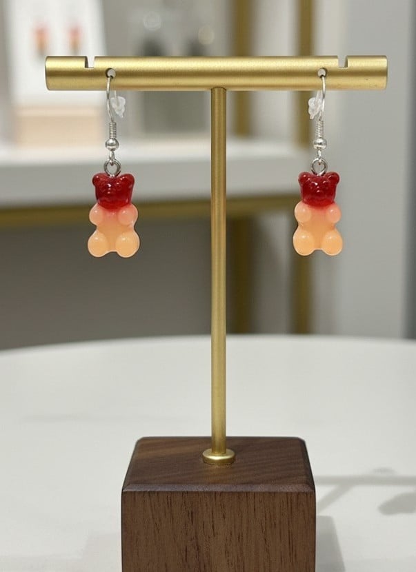 Pair of handmade sunset gummy bear resin earrings displayed on a gold jewellery stand