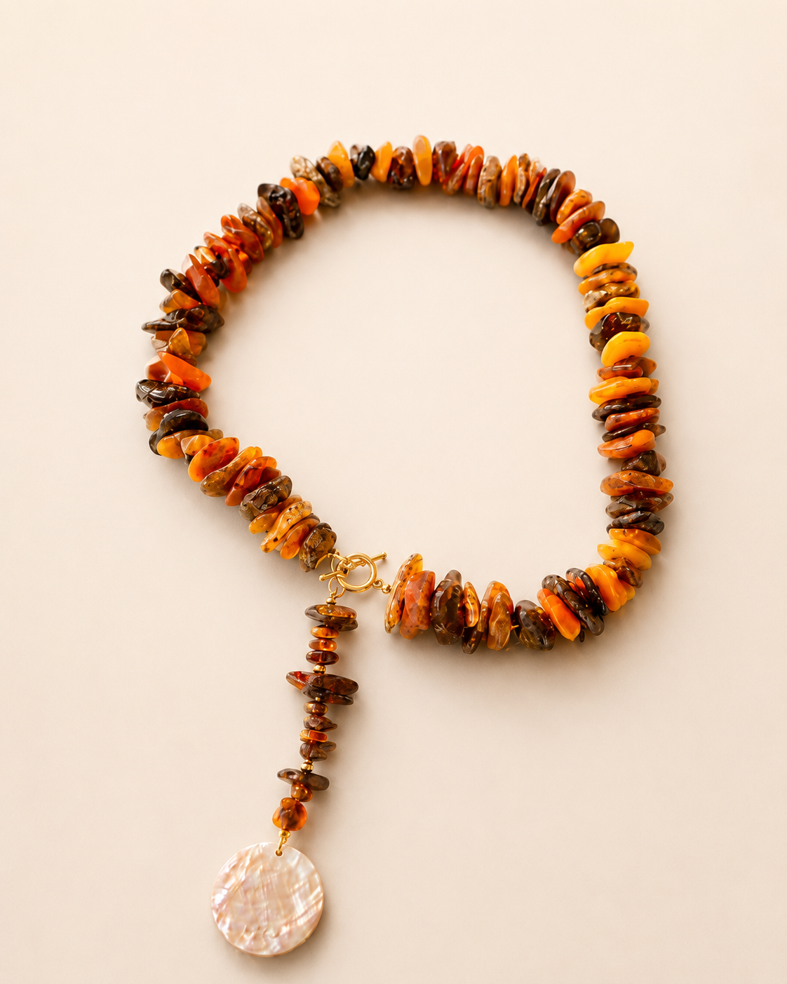 Collana in ambra baltica naturale grezza con ciondolo in madreperla naturale fotografata su sfondo chiaro – gioiello artigianale Lumen Jewels