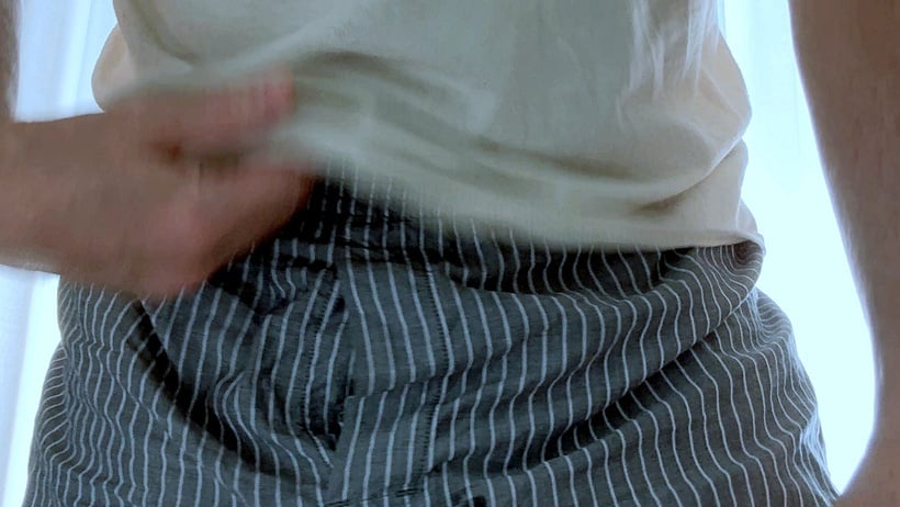 Close-up detail of PRiCE Douglas wearing gray striped boxer shorts and a white T-shirt, photographed in natural morning window light.