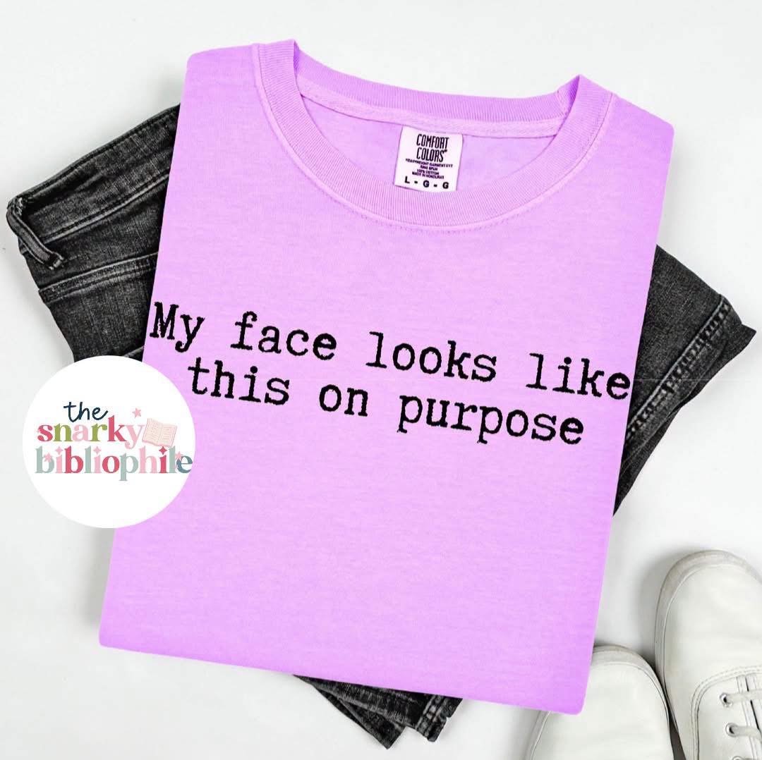 Neon purple comfort colors t-shirt with black typewriter print that says my face looks like this on purpose. Unisex fit and savailable in sizes small through three x.