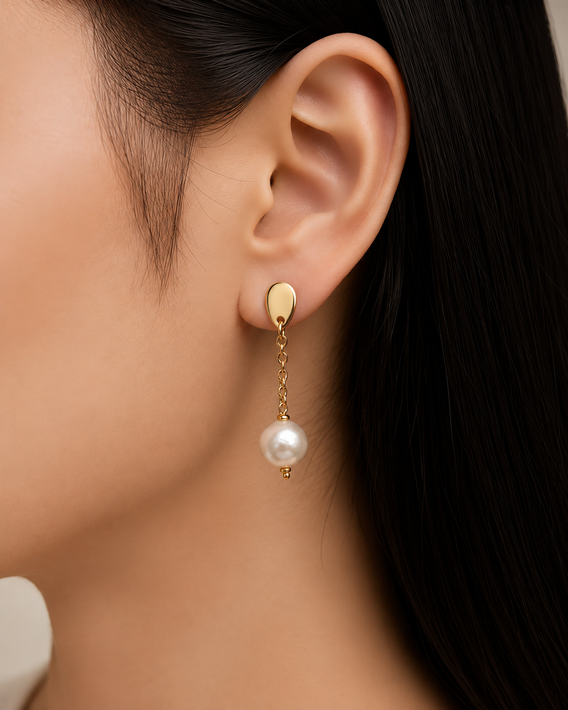 Primo piano degli orecchini con perla bianca naturale da 8 mm e base color oro indossati.