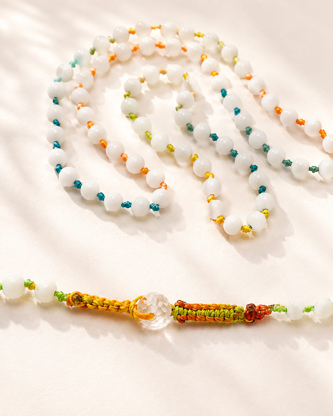 Collana lunga in agata bianca naturale da 3 mm indossata con abito bianco. della collana in agata bianca naturale da 3 mm con chiusura a bottoncino in cristallo.