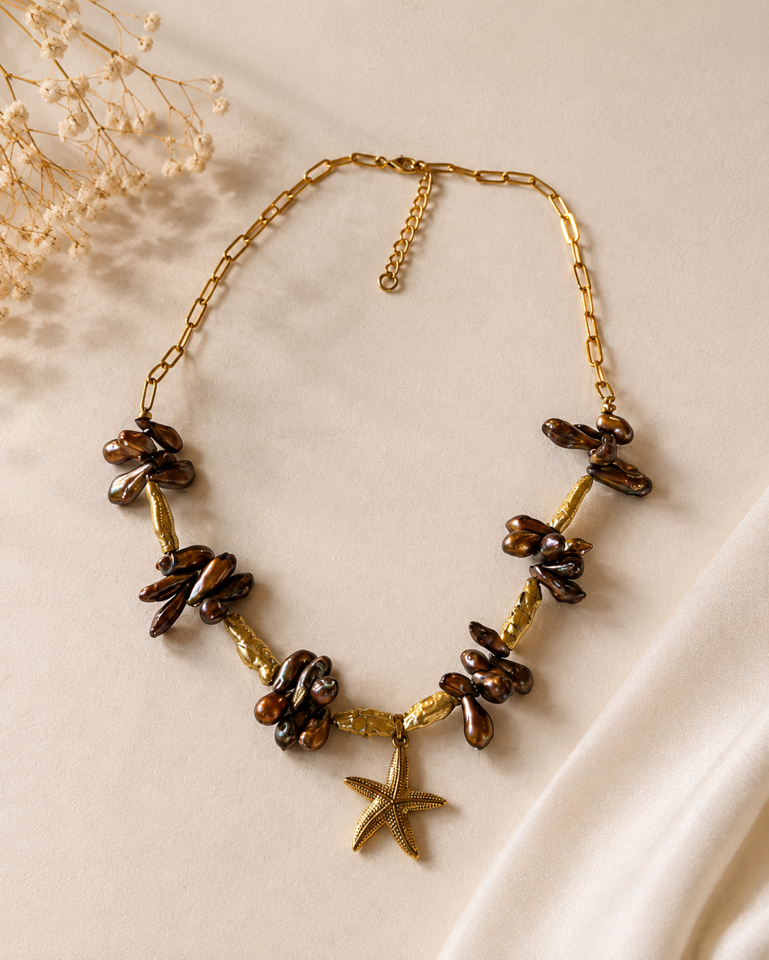 Collana con perle di fiume e stella marina fotografata su sfondo chiaro minimalista.