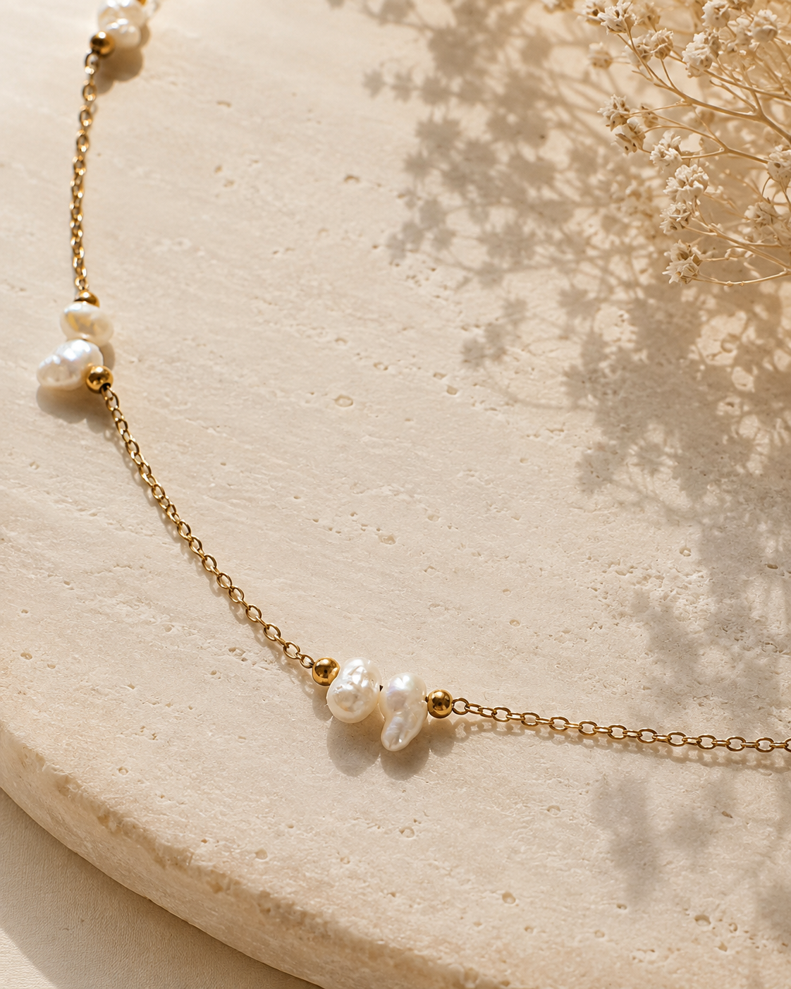Dettaglio della collana minimal in acciaio color oro con perle di fiume naturali.