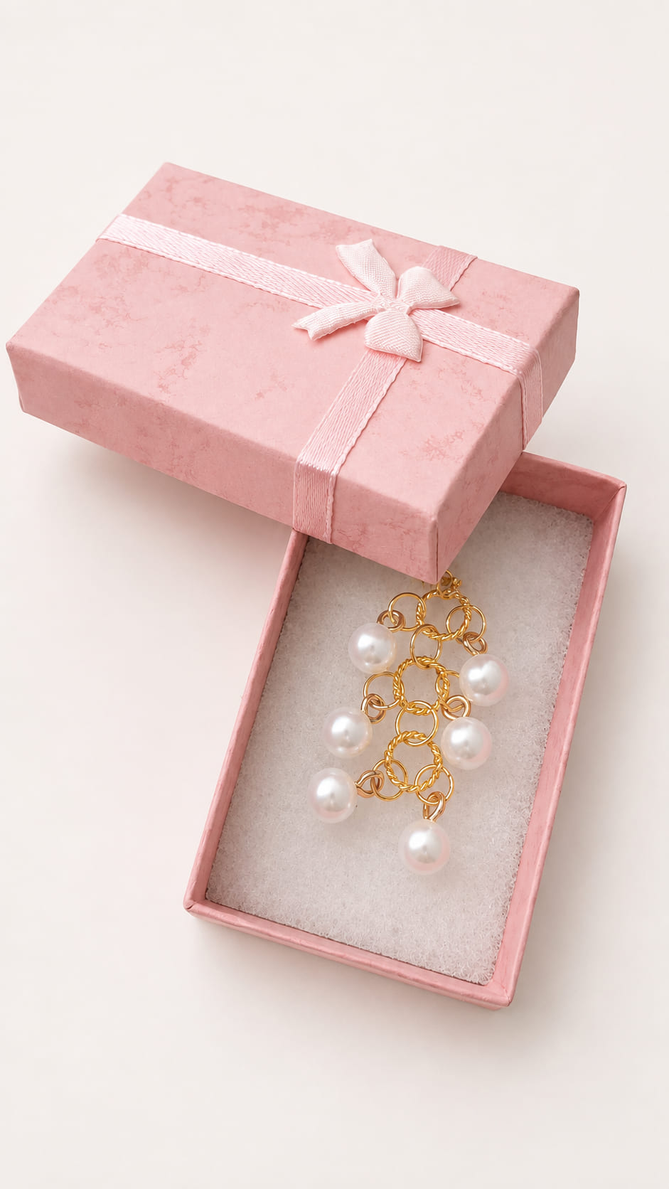 Handmade bridal bouquet memory charm featuring a gold chain mesh layout with dangling lustrous faux pearls inside an open pink textured gift box with a bow.