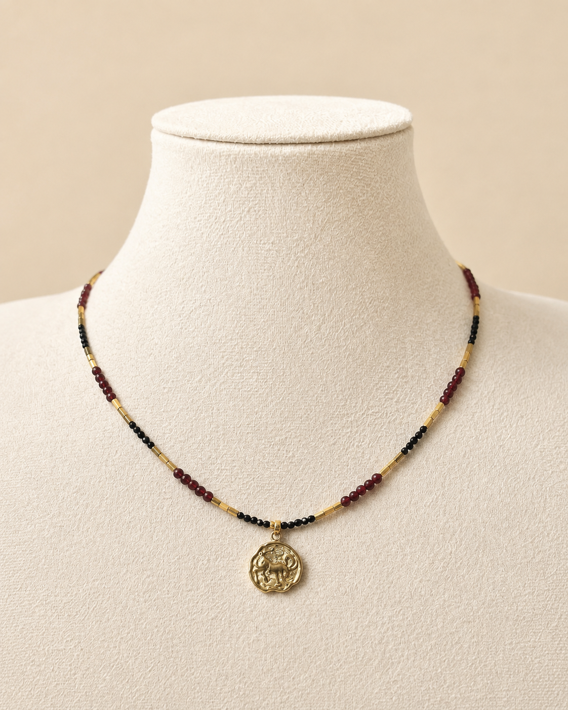 Collana Capricorno in onice nero dorato, ossidiana nera e granato rosso indossata su manichino