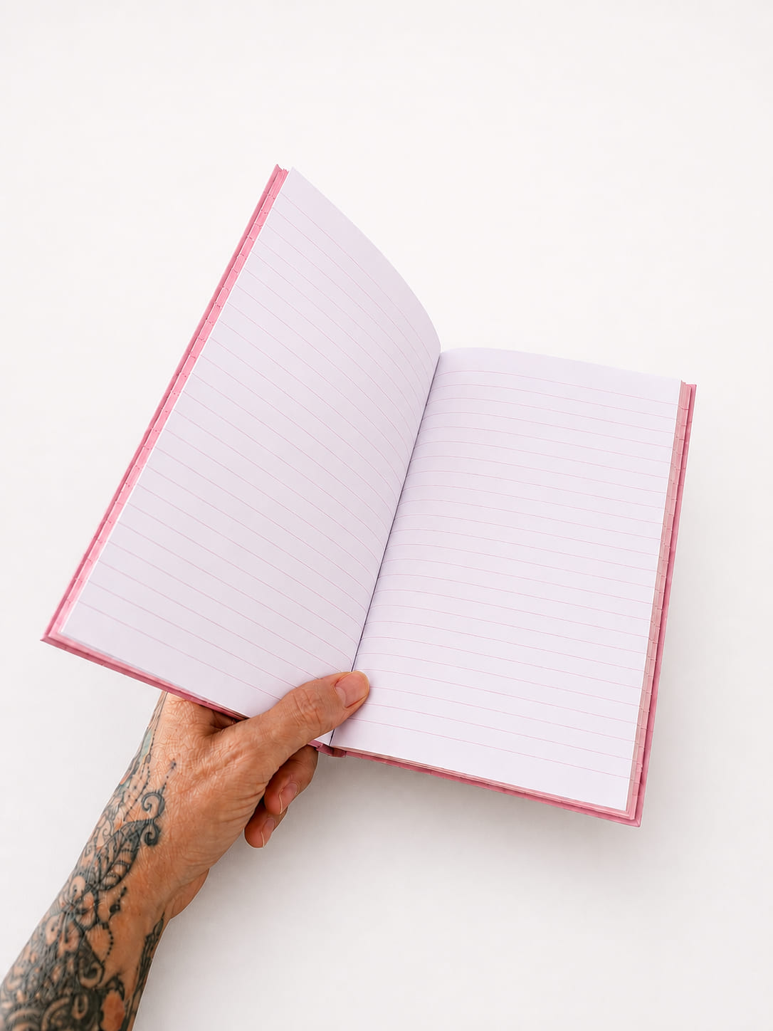 Open pink notebook showing white ruled pages for writing, journalling, notes and lists