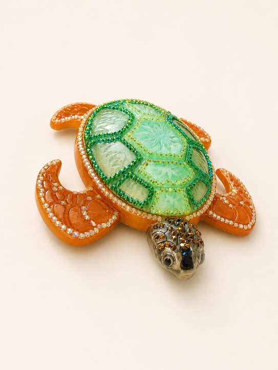 Angled view of sparkling resin sea turtle ornament showing green shell, bronze-orange flippers and decorative head