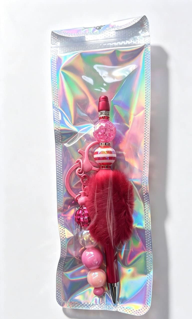 A pink custom novelty pen and fluffy pom-pom keychain set packaged inside a glossy, eye-catching holographic silver presentation pouch.