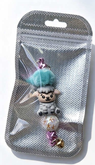 A Sweet and Fluffy Grey Sheep Handmade Keychain from Sparkling Resin Delights, packed inside a clear-fronted silver holographic retail bag with a hang hole.
