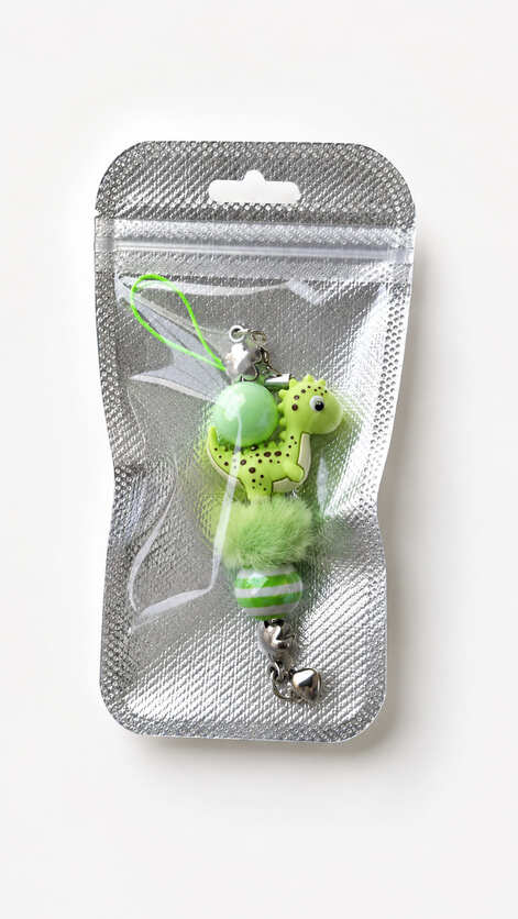 A playful lime green dinosaur phone charm and bag accent from Sparkling Resin Delights, securely sealed inside a clear-fronted silver holographic retail presentation pouch with a hang hole.