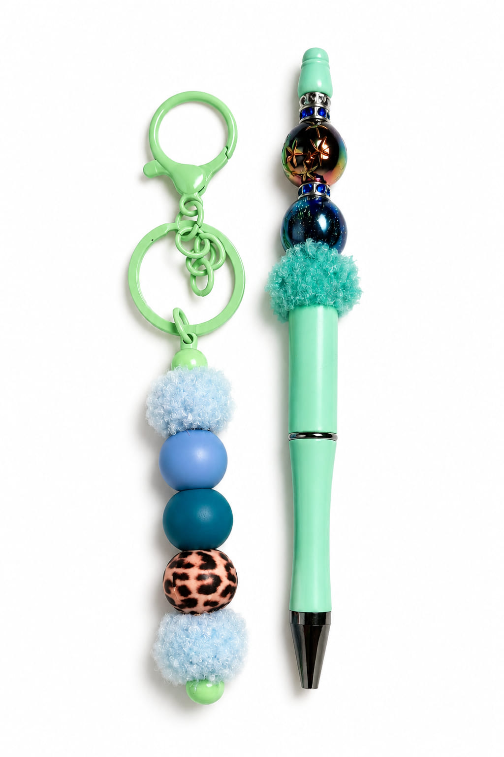 Close-up layout of the Mint and Teal Cheetah Duo custom stationery set by Sparkling Resin Delights, showcasing a mint green beadable pen with blue rhinestone spacers, a textured teal pom-pom, and iridescent beads next to a matching mint green lobster-clas