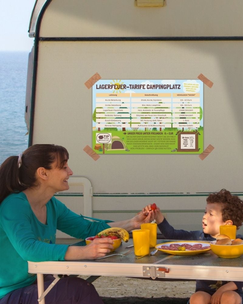 Preisliste für den Campingplatz in der hellen Variante am Wohnwagen, davor ein gedeckter Campingtisch am Meer