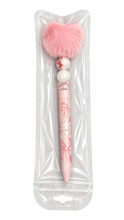 Handmade Betty Bow custom beaded pen topped with a fluffy pink heart-shaped pom pom, sealed inside protective clear hanging retail packaging.