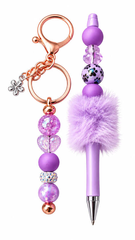 A luxury purple stationery set showing a matching keychain and ballpoint pen, featuring a purple leopard print bead, a silver flower charm, glittering rhinestones, and a fluffy violet pom-pom.