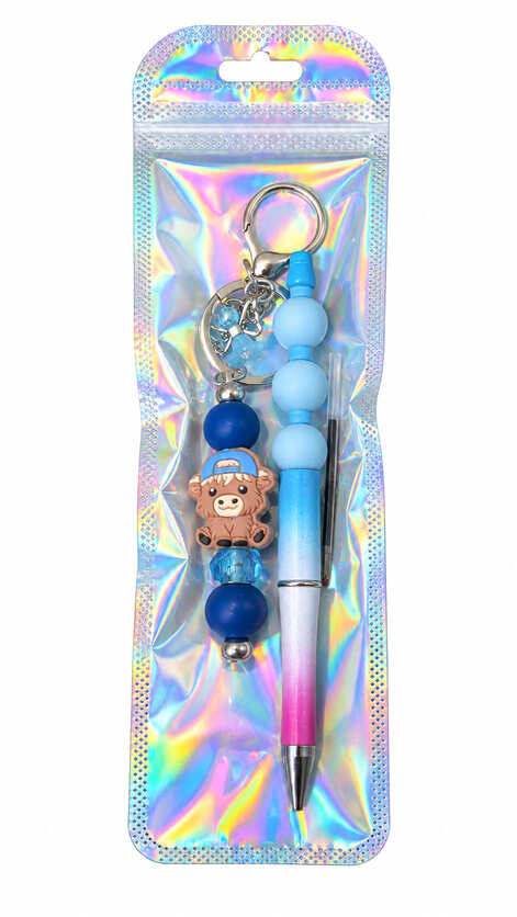 A highland cow and blue ombre beaded pen and matching keychain set displayed inside a glossy, iridescent holographic retail pouch.
