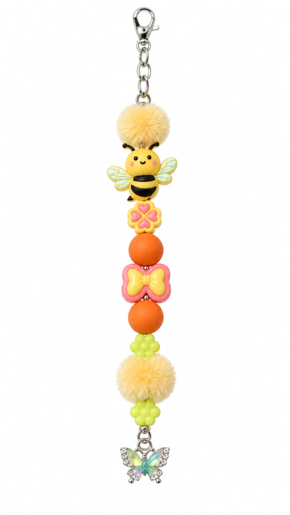 A close-up view of a novelty garden-themed fidget strap showing a silver lobster clasp, two fluffy yellow pom-poms, a smiling cartoon honey bee bead, a yellow heart-clover, a pink bow bead, orange spheres, and a rhinestone-lined butterfly charm at the bot