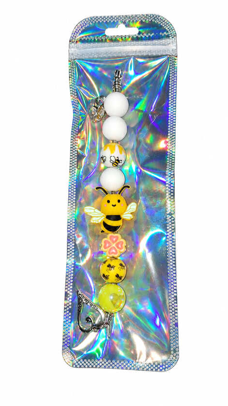 A cute bumble bee silicone beaded fidget charm displayed inside a glossy, iridescent holographic retail pouch