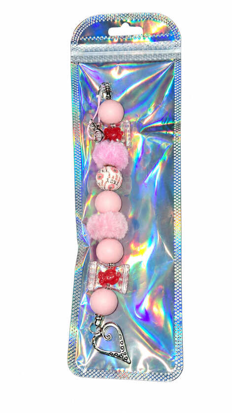 A soft baby pink candy and red flower silicone beaded fidget charm displayed inside a glossy, iridescent holographic retail pouch.