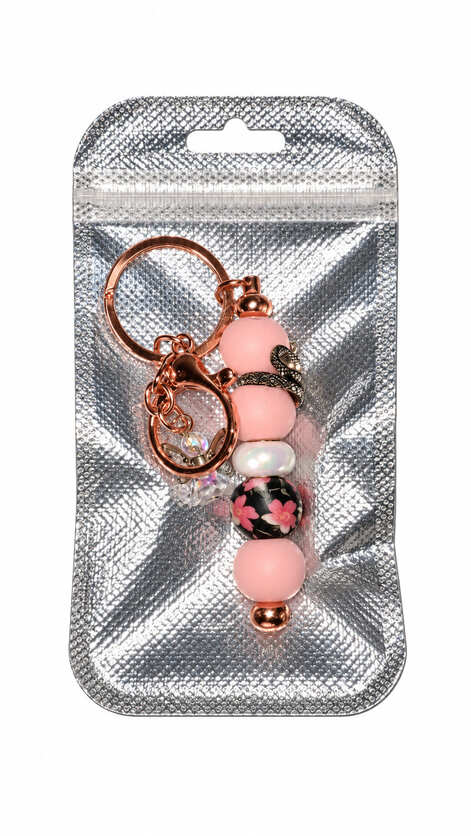 Handmade pink floral snake and angel bag charm presented in a shimmering silver gift pouch
